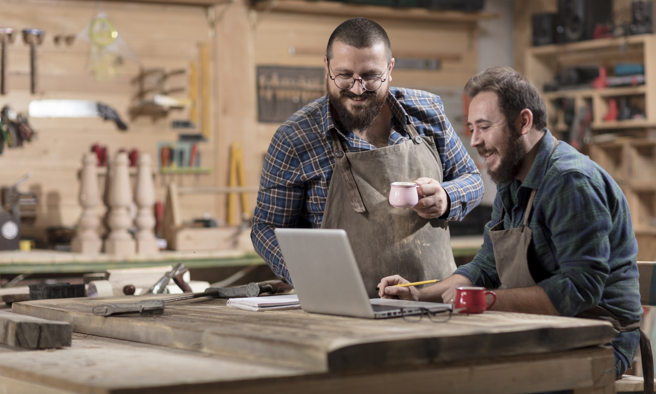 Two,Wood,Designer,Working,With,Laptop,In,Workshop. Small Business Owners Reviewing Their Finances